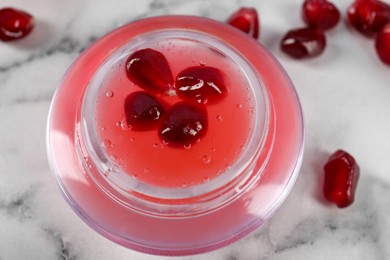 Photo of Cosmetic product made of pomegranate on white marble table, above view. DIY beauty recipe