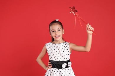 Photo of Cute girl with small crown and magic wand on red background. Little princess