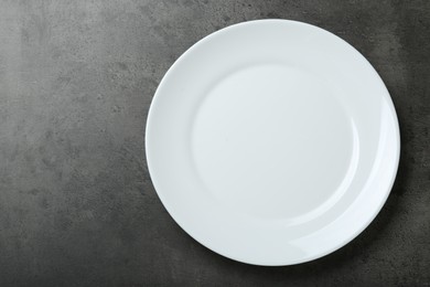 Photo of Empty white ceramic plate on grey table, top view. Space for text