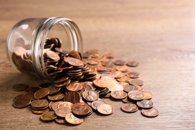 Glass jar with coins on wooden table, space for text. Money saving concept