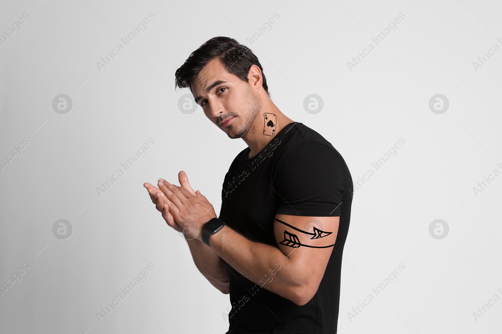 Image of Handsome man with beautiful tattoo sketches on light grey background