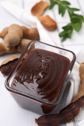 Photo of Bowl of tasty tamarind sauce and fresh pods on light table