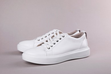 Photo of Pair of stylish white sneakers on grey background