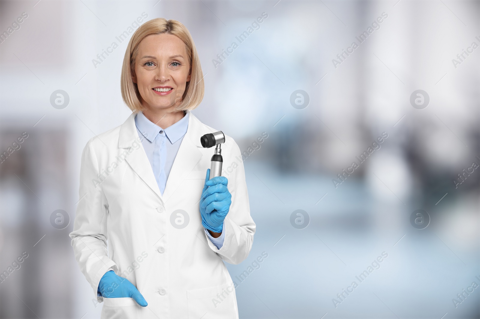 Image of Professional dermatologist with dermatoscope on blurred background, space for text