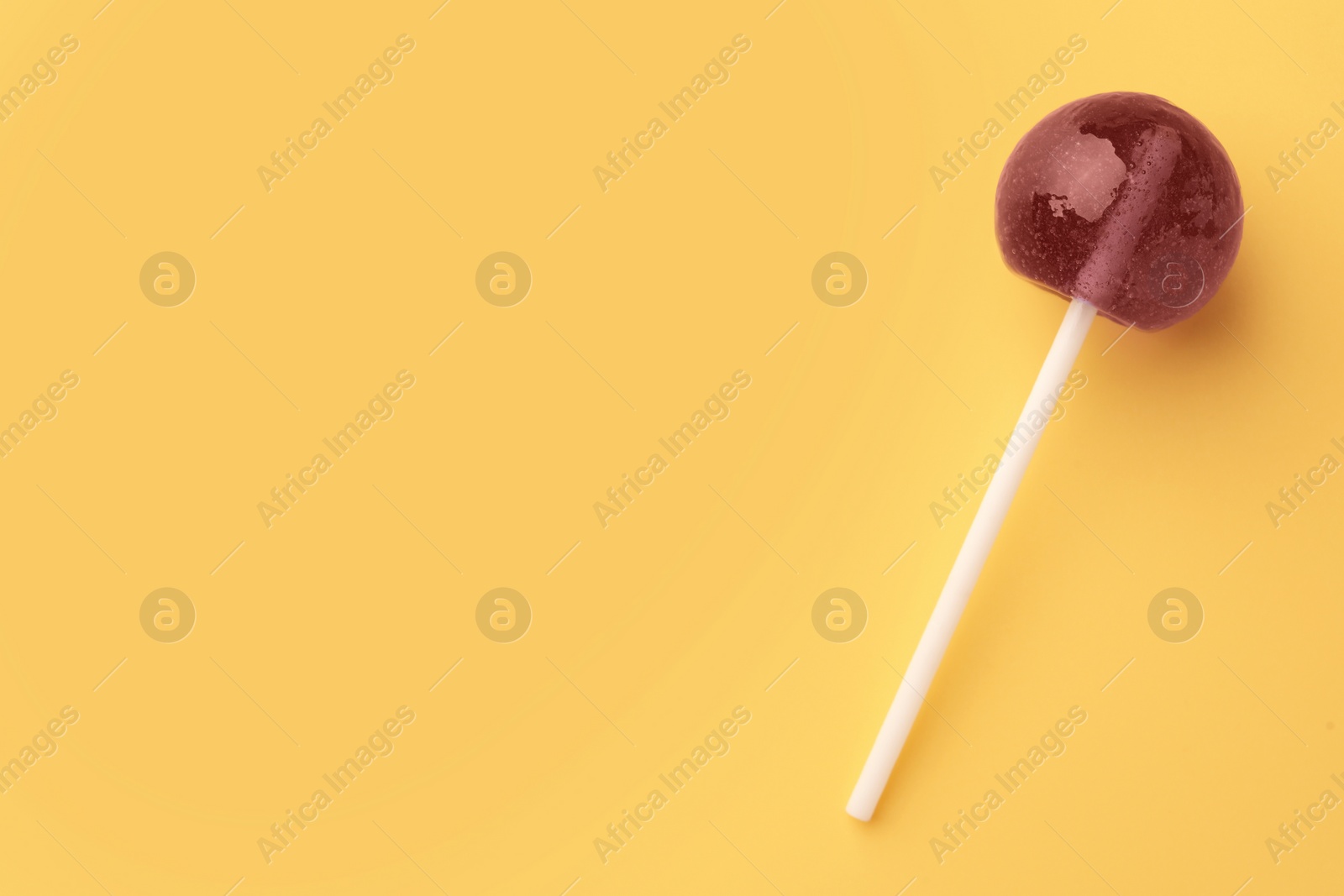 Photo of Tasty lollipop on yellow background, top view. Space for text