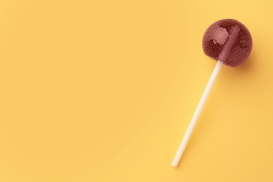 Photo of Tasty lollipop on yellow background, top view. Space for text