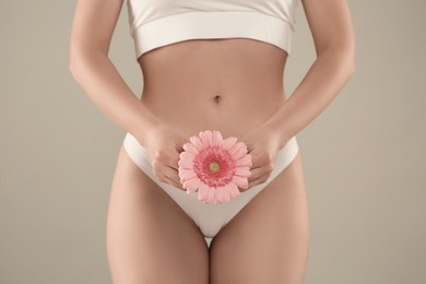 Photo of Gynecology. Woman in underwear with gerbera flower on green background, closeup