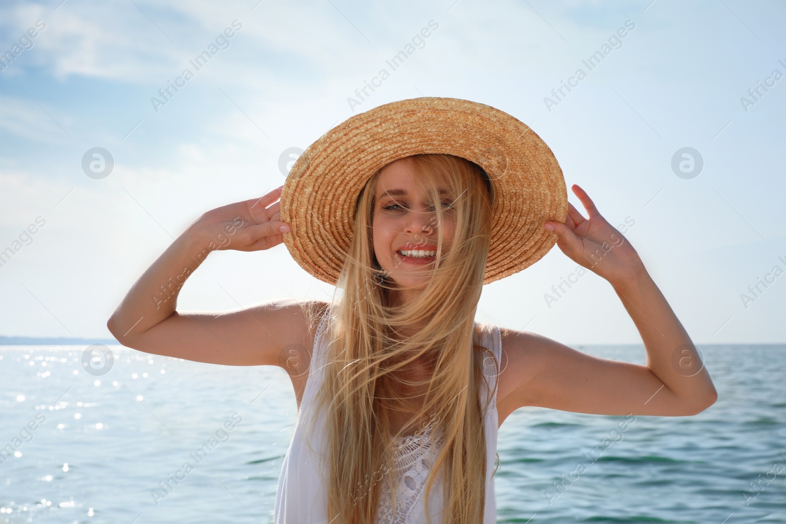 Photo of Beautiful young woman with straw hat near sea on sunny day in summer