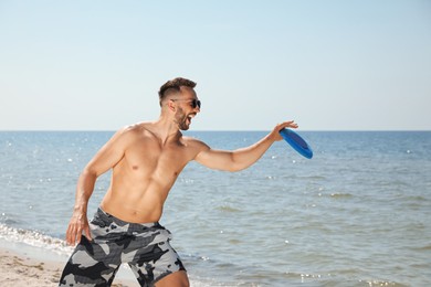 Photo of Happy man catching flying disk at beach on sunny day