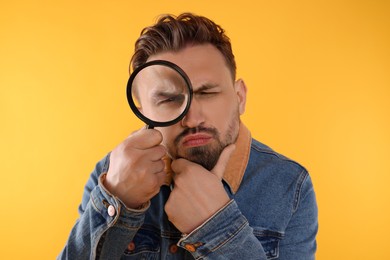Photo of Handsome man looking through magnifier on yellow background