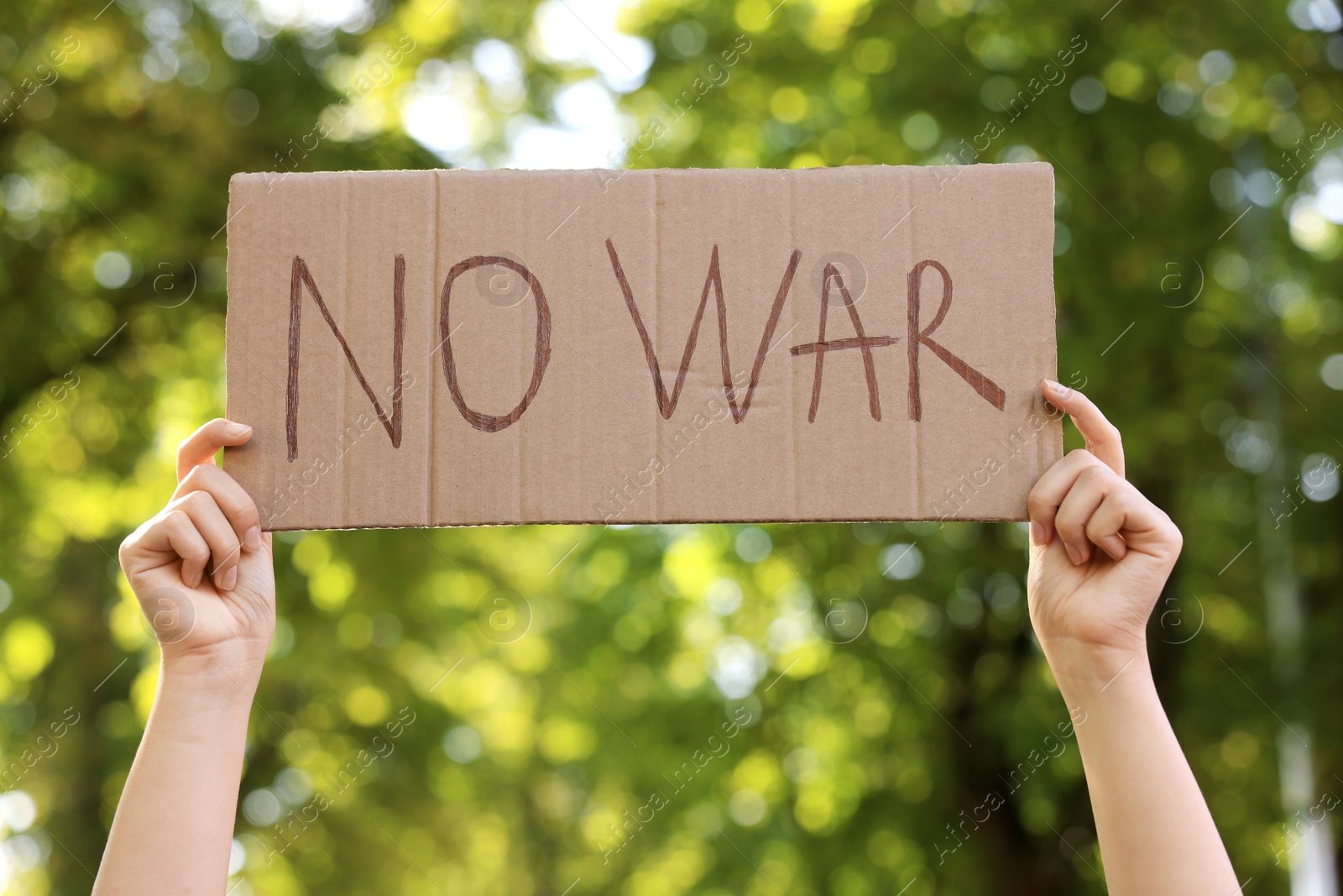 Photo of Woman holding poster with words No War in park, closeup