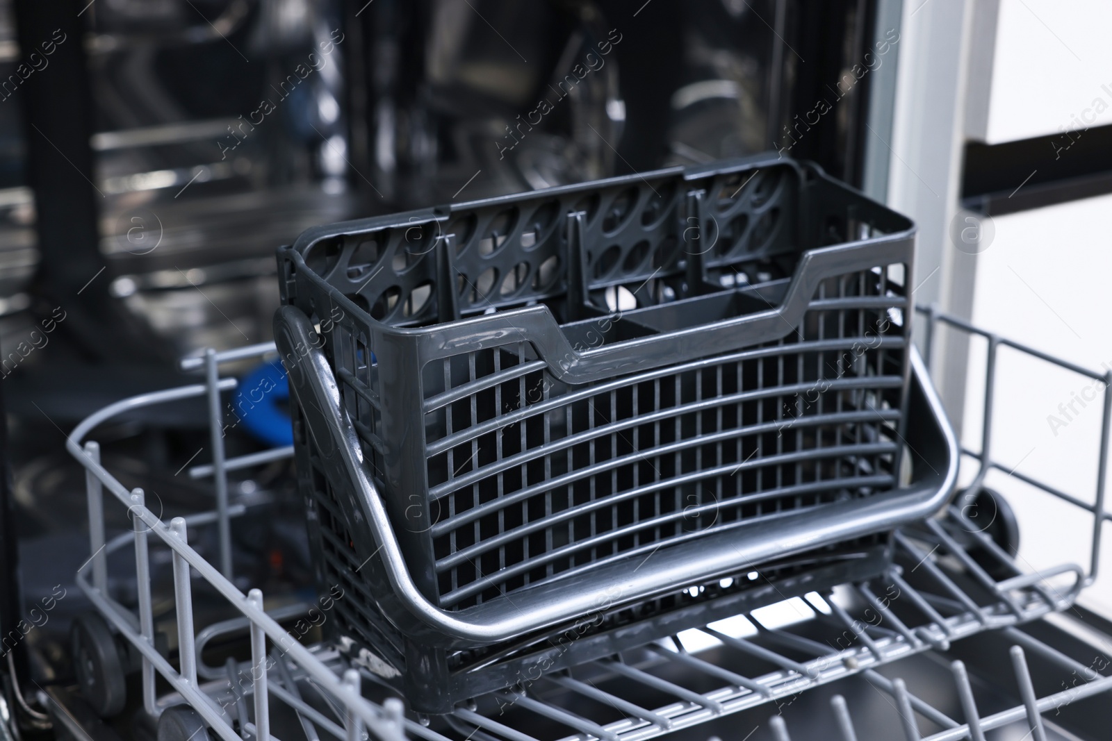 Photo of Open clean empty dishwasher indoors, closeup. Home appliance