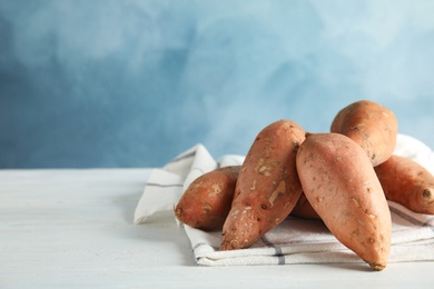 Photo of Sweet potatoes on table against color background. Space for text