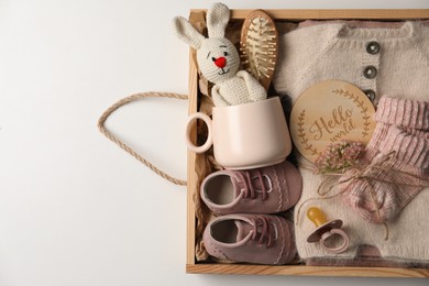 Photo of Box with baby clothes, shoes and accessories on light background, top view. Space for text