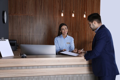 Photo of Receptionist registering client at desk in lobby