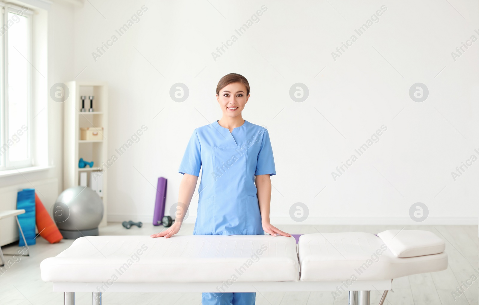 Photo of Young physiotherapist near massage table in rehabilitation center