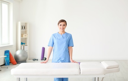 Young physiotherapist near massage table in rehabilitation center