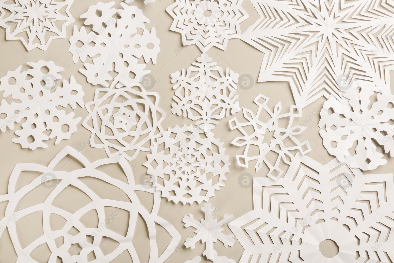 Photo of Many paper snowflakes on light grey background, flat lay