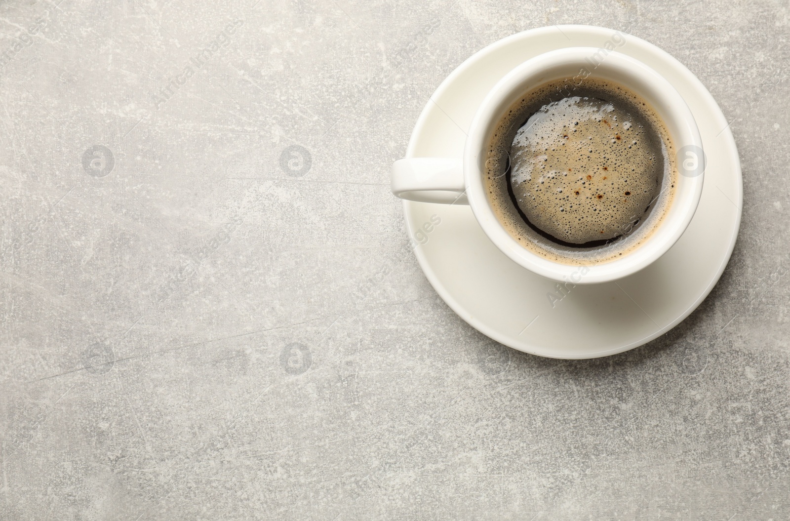 Photo of Cup of aromatic coffee on light grey table, top view. Space for text