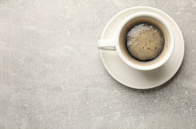 Photo of Cup of aromatic coffee on light grey table, top view. Space for text