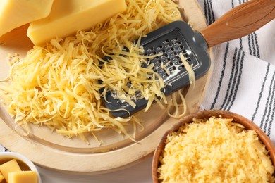 Photo of Grated, whole piece of cheese and grater on table, top view