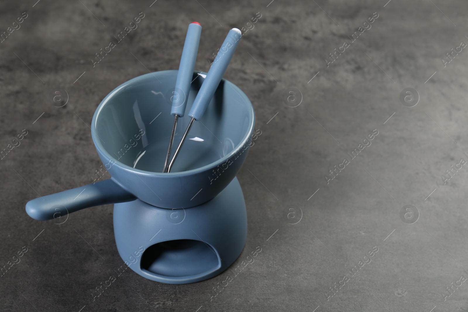 Photo of Fondue set on grey textured table, space for text