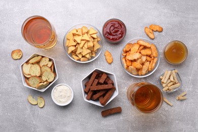 Different crispy rusks, beer and dip sauces on light table, flat lay