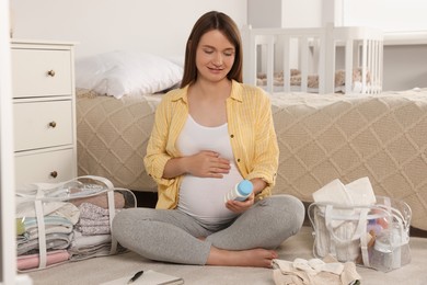 Photo of Pregnant woman packing baby stuff to bring into maternity hospital on floor in bedroom