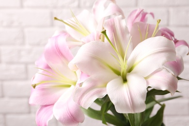 Photo of Beautiful blooming lily flowers on brick wall background