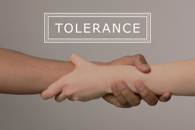 Image of Tolerance, support and cooperation concept. People of different races holding hands on light grey background, closeup
