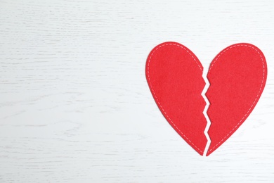 Photo of Broken red heart on wooden background, top view with space for text