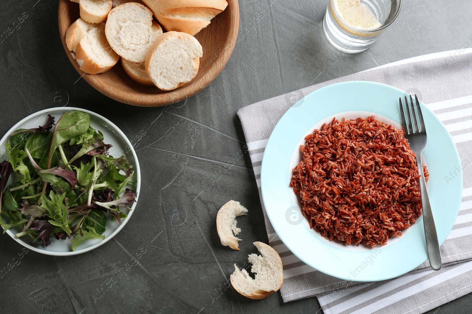 Photo of Tasty brown rice served on dark grey table, flat lay