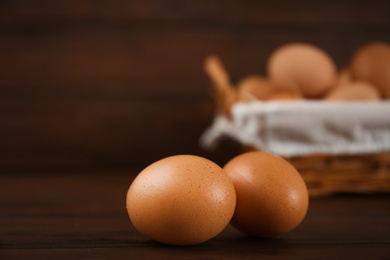 Photo of Raw chicken eggs on wooden table, closeup. Space for text