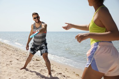 Photo of Couple playing with flying disk at beach on sunny day