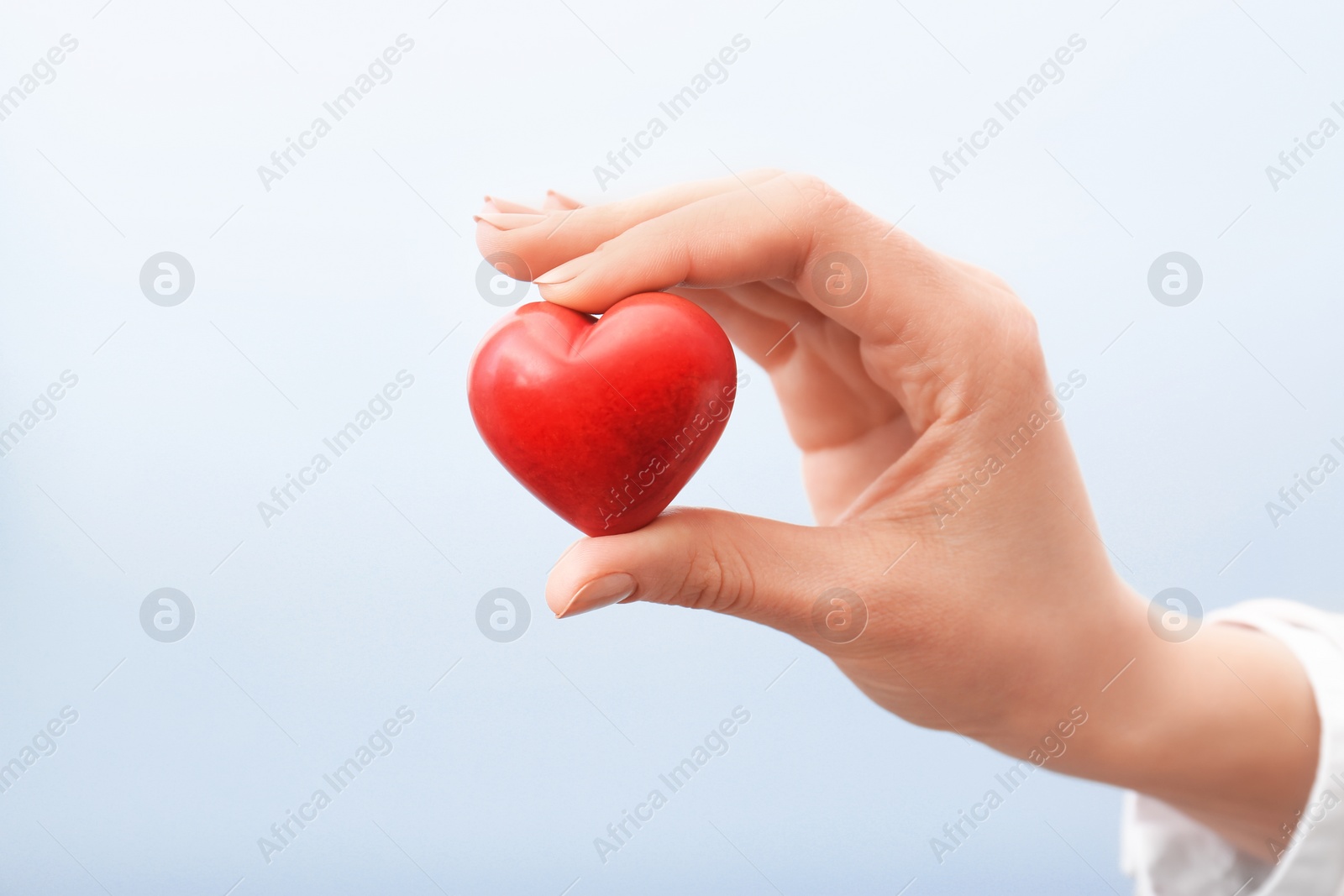 Photo of Woman holding small red heart on light background. Heart attack concept