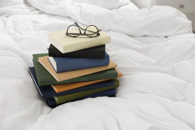 Photo of Hardcover books and glasses on white bed