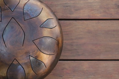 Photo of Steel tongue drum on wooden table, top view. Space for text