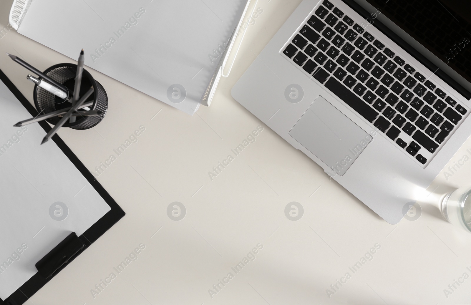 Photo of Modern laptop and stationery on white table, flat lay. Space for text