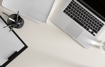 Modern laptop and stationery on white table, flat lay. Space for text