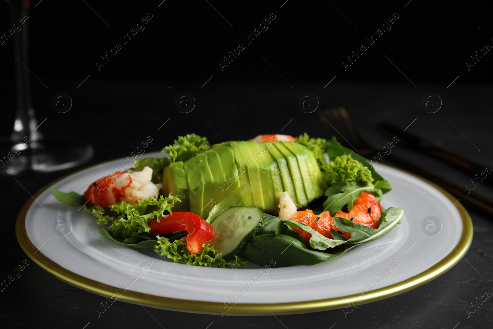 Photo of Delicious avocado salad with shrimps on dark table