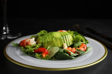 Delicious avocado salad with shrimps on dark table