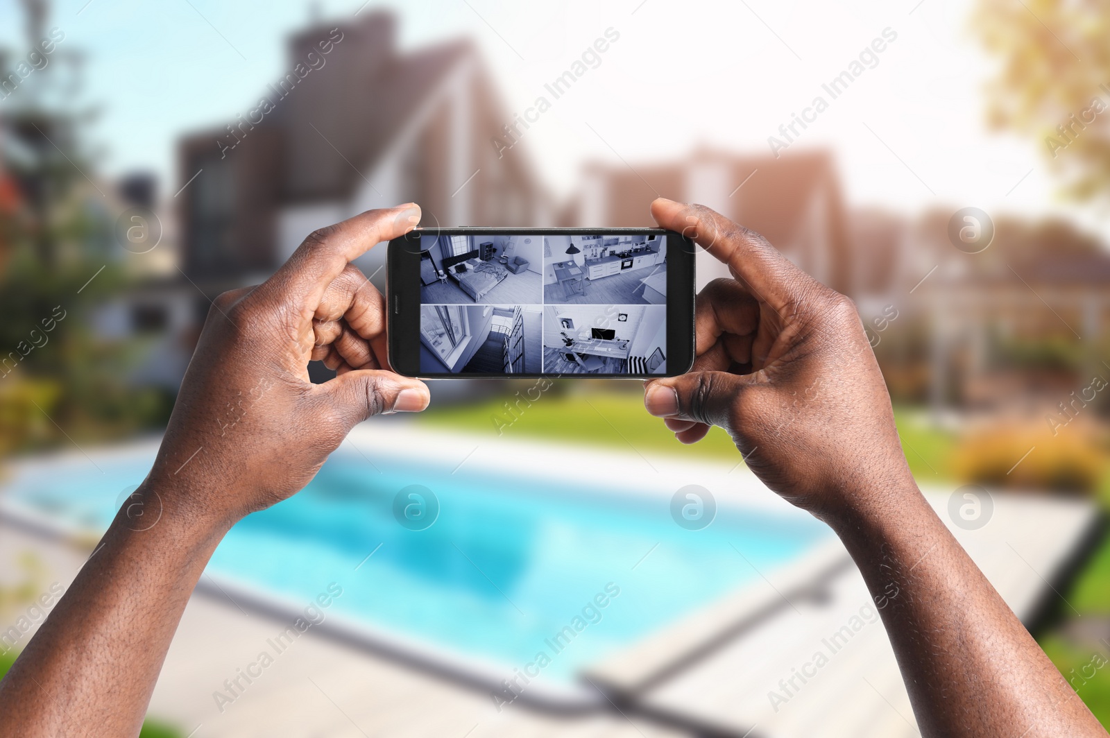 Image of African-American man monitoring modern CCTV cameras on smartphone near his house, closeup. Home security system