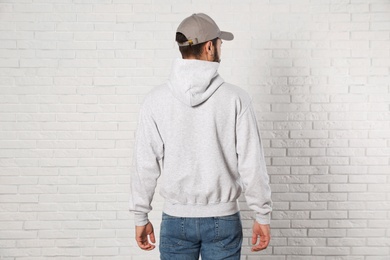 Photo of Young man in sweater at brick wall. Mock up for design