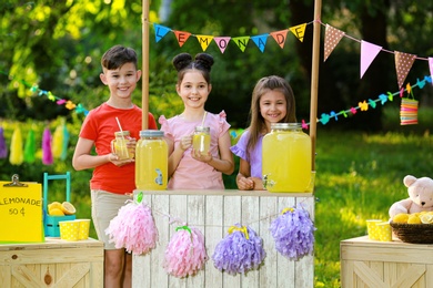 Photo of Cute little children at lemonade stand in park. Summer refreshing natural drink