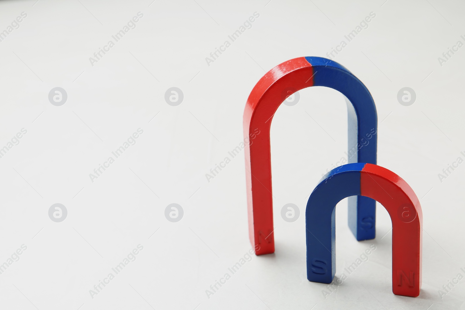 Photo of Red and blue horseshoe magnets on white background. Space for text