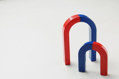 Photo of Red and blue horseshoe magnets on white background. Space for text