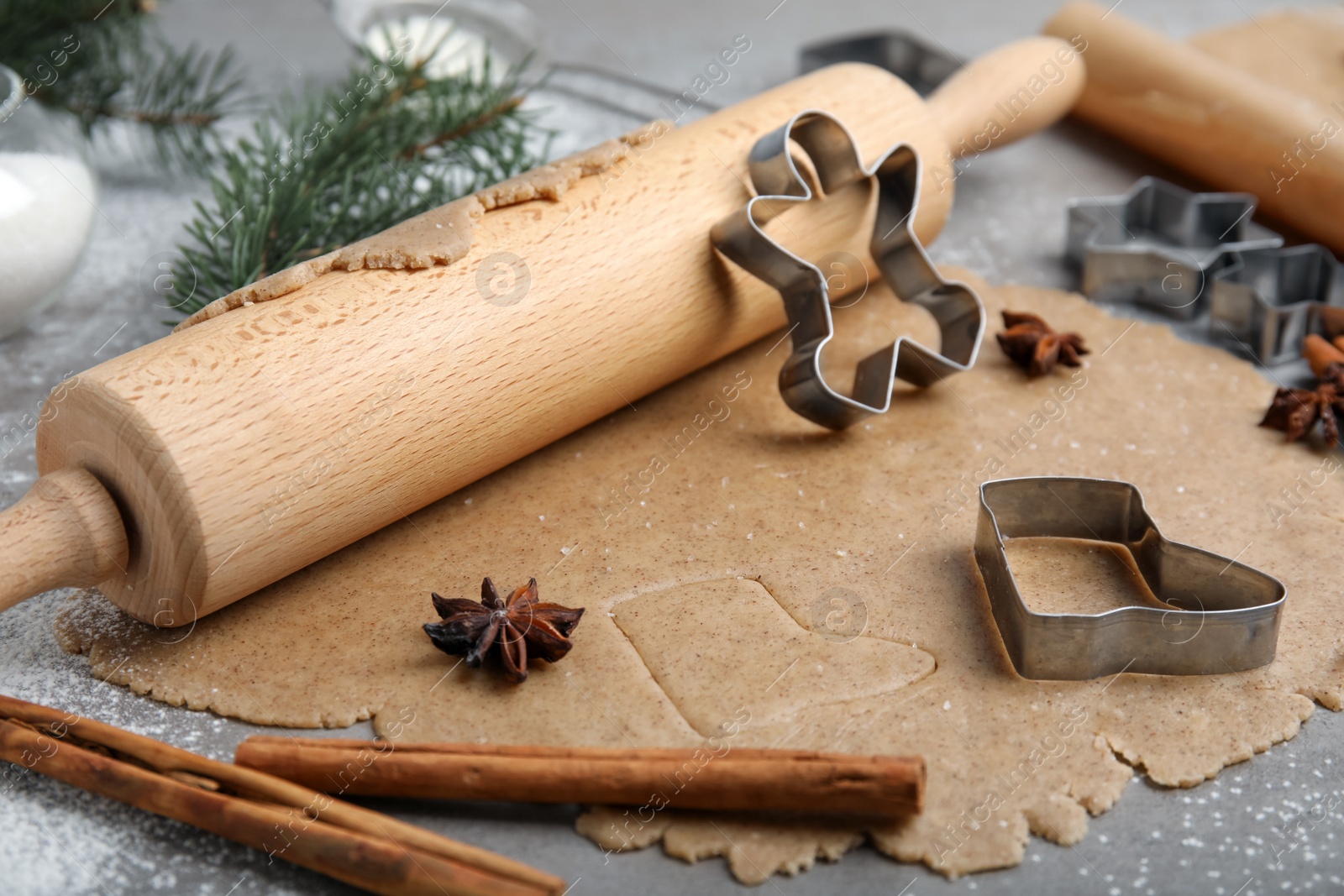 Photo of Homemade Christmas biscuits. Raw dough, rolling pin and cookie cutters on grey table, closeup