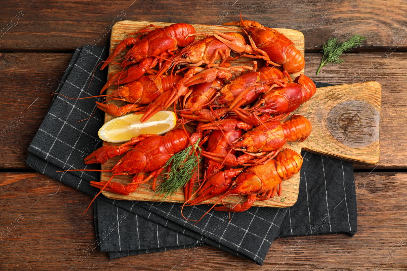 Photo of Delicious boiled crayfishes with lemon and dill on wooden table, top view