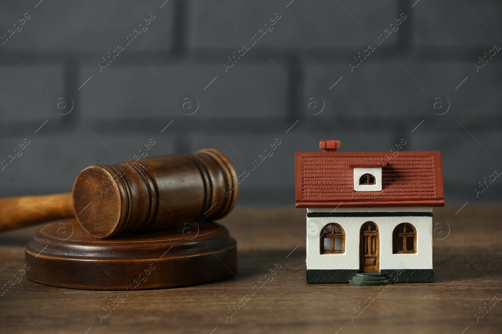 Photo of Construction and land law concepts. House model and gavel on wooden table, closeup