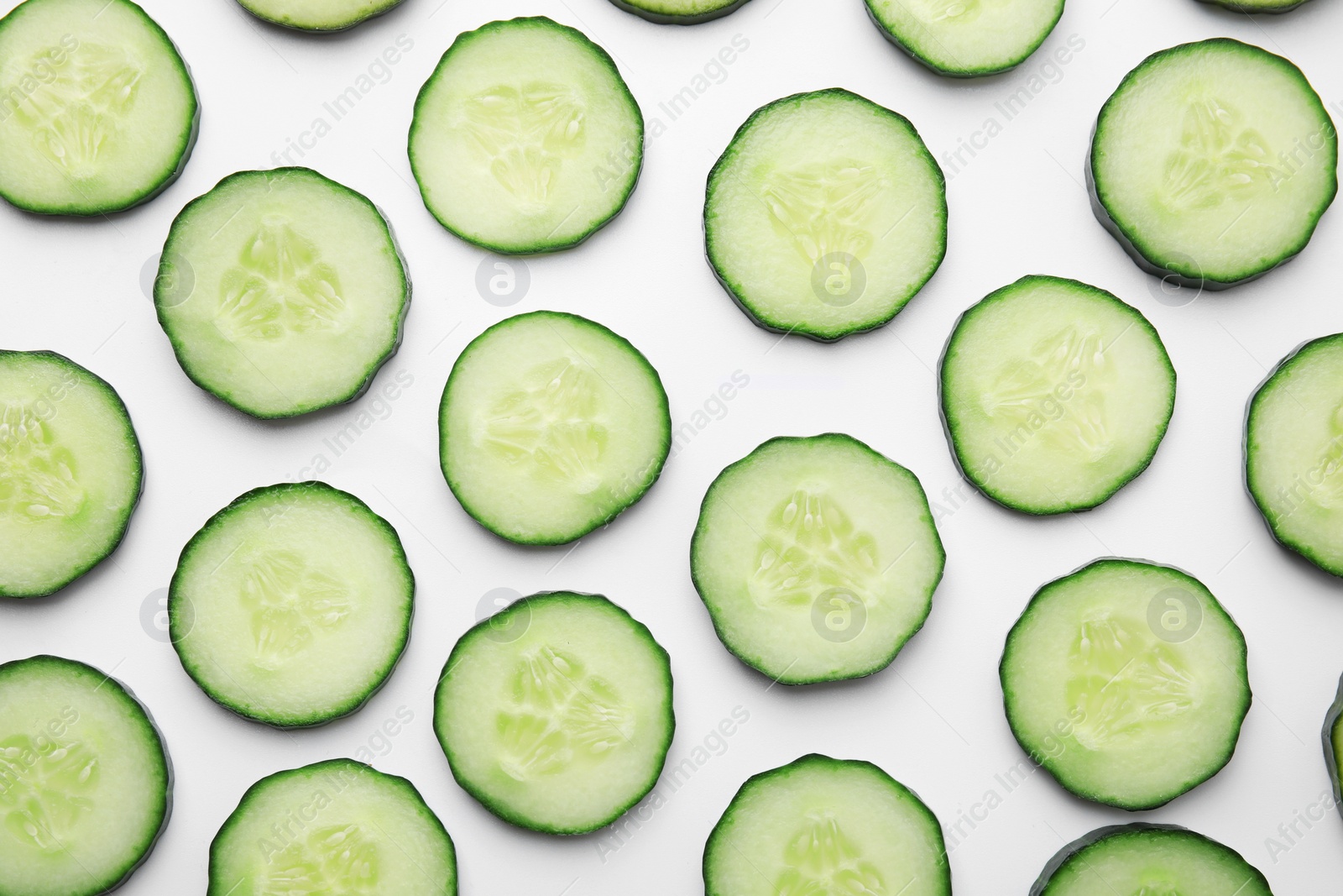 Photo of Fresh slices of cucumbers on white background, top view